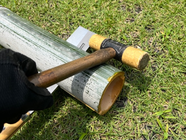 竹を鉈とハンマーで割る